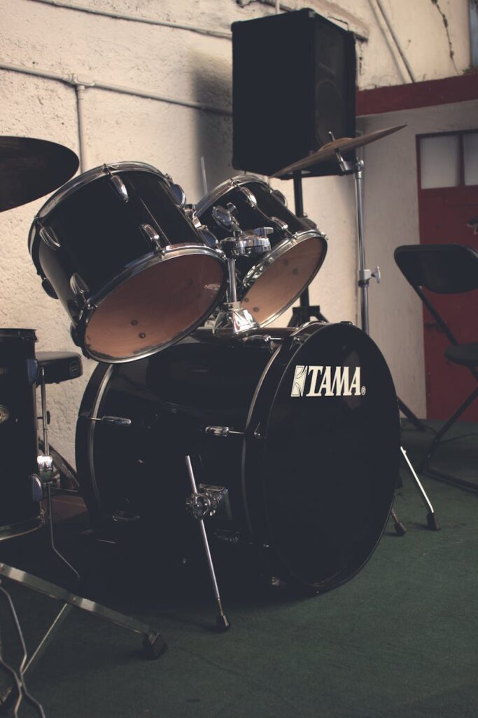 Black drum set in a music rehearsal room, featuring a Tama bass drum.