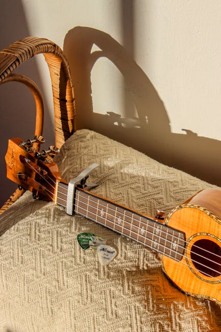 Ukulele resting on a wicker chair with guitar picks in sunlight, creating a cozy musical scene.