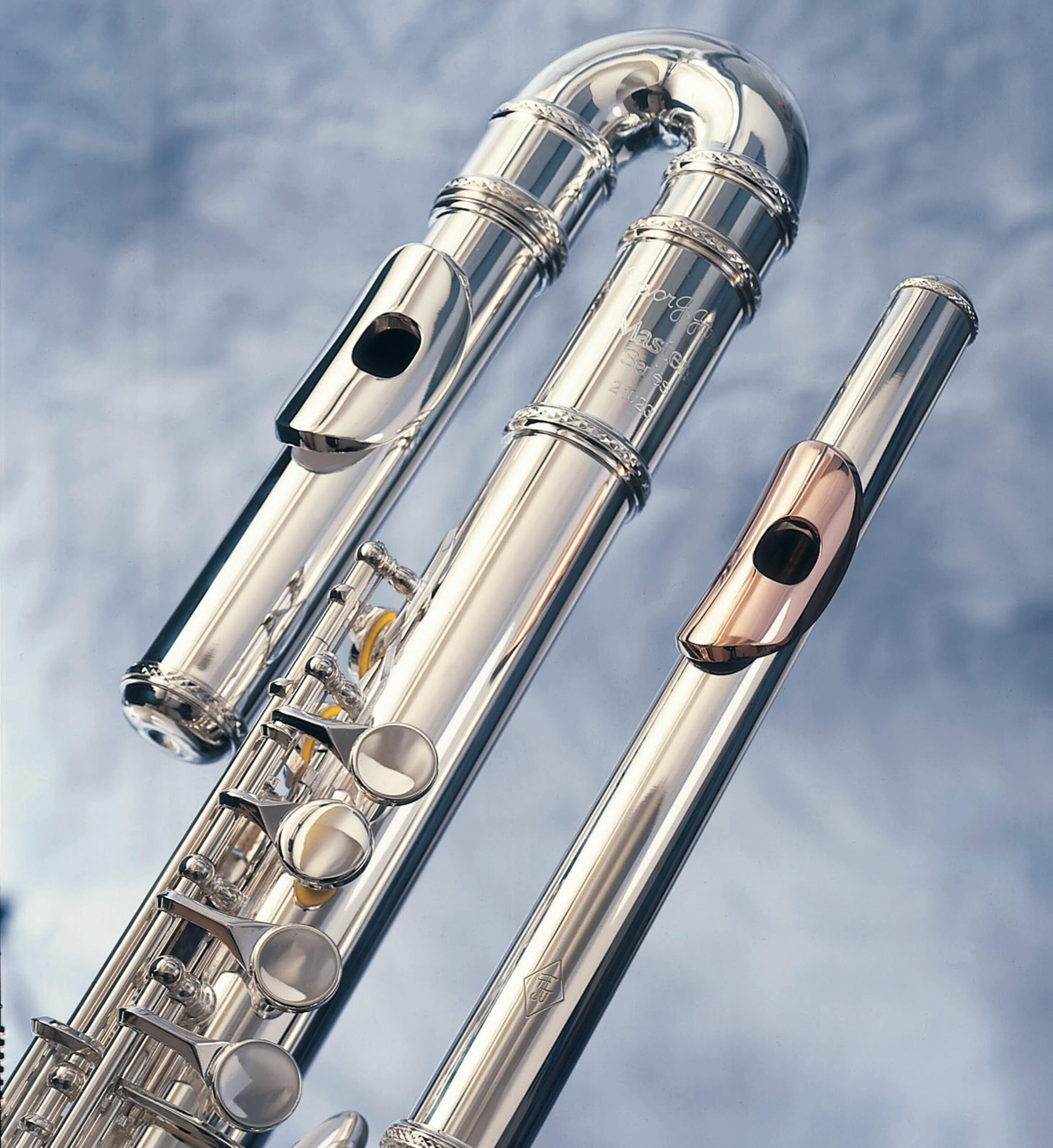 Close-up of silver and gold flutes showcasing intricate details and craftsmanship against a soft backdrop.