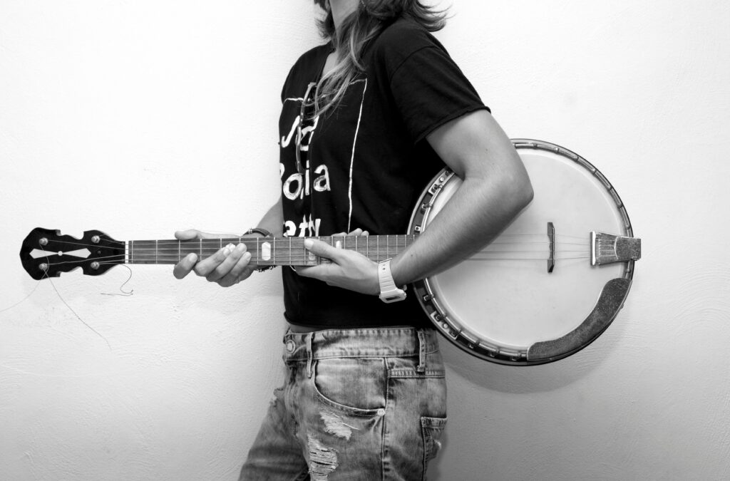 A young musician holding a banjo, captured in a studio setting. Black and white photography.