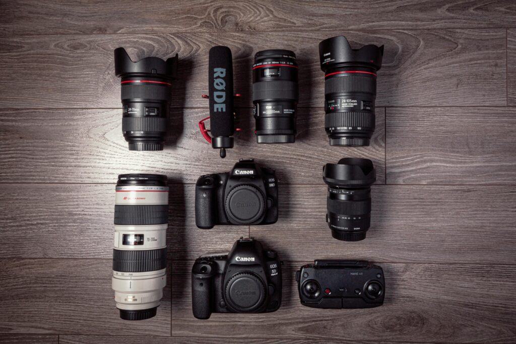 Flat lay of professional photography equipment including cameras, lenses, and microphone.