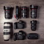 Flat lay of professional photography equipment including cameras, lenses, and microphone.