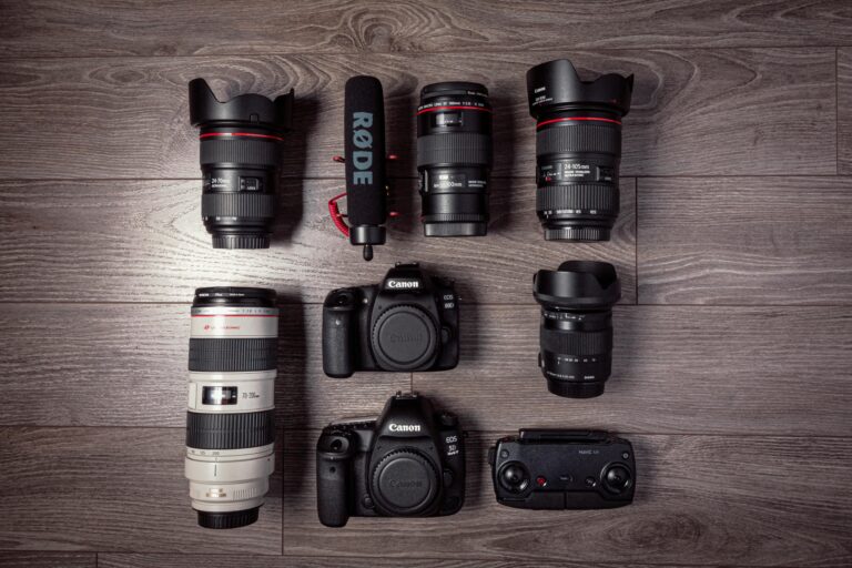 Flat lay of professional photography equipment including cameras, lenses, and microphone.